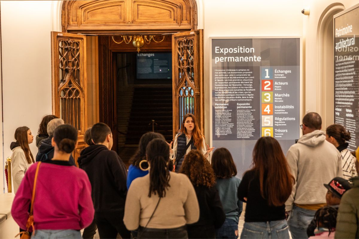 A museum guide welcoming a group at the entrance to the permanent exhibition