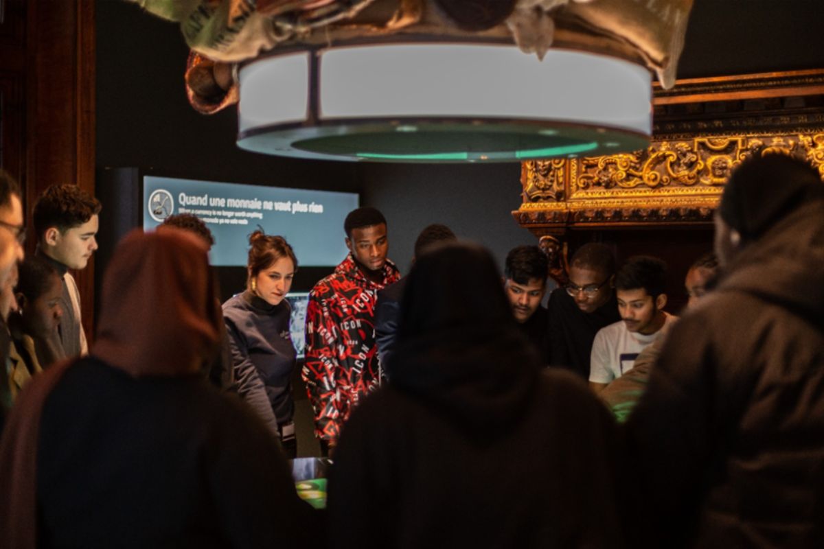 A group of teenagers gathered around an interactive table with a museum guide